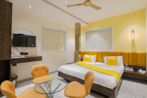孟买The Cattleya Hotel - Near Marol, Andheri East, Mumbai的一间卧室配有一张床、两把椅子和一台电视