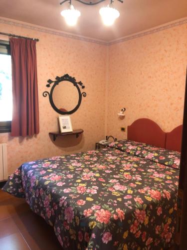 阿贝托内派尼尔利一号酒店的一间卧室配有一张带花卉床罩和镜子的床
