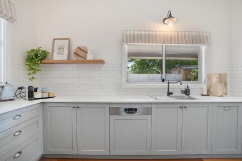 塞斯诺克‘Endsleigh Cottage’ - Modern Luxury, Aged Charm的厨房配有白色橱柜、水槽和窗户。