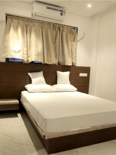 UlhāsnagarHotel Majestic的一间卧室配有一张带白色床单的床和一扇窗户。