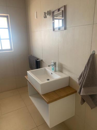 奥奇瓦龙戈Otjibamba Lodge的浴室设有白色水槽和镜子
