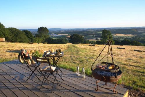 West BagboroughTilbury Shepherd Huts with Hot Tubs Plus Holiday Cottages的桌子和两把椅子以及甲板上的火坑