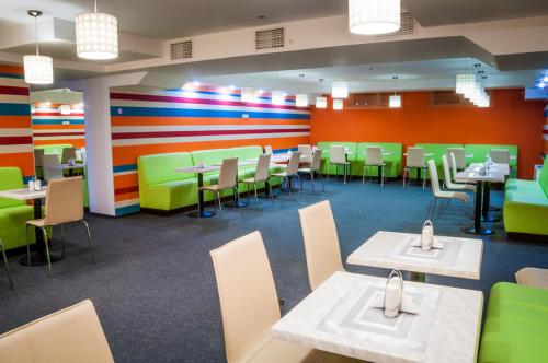 基辅Raziotel Kyiv (Boryspilska)的餐厅设有桌椅和色彩缤纷的墙壁
