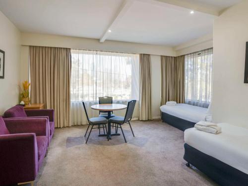 墨尔本北墨尔本美居酒店的酒店客房带一张床、一张桌子和椅子