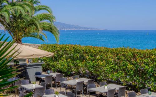 芒通Best Western Premier Hotel Prince de Galles的一间设有桌椅的海洋餐厅