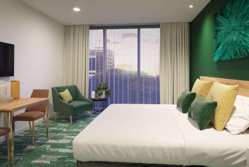 奥克兰La Quinta by Wyndham Ellerslie Auckland的酒店客房设有床、桌子和窗户。