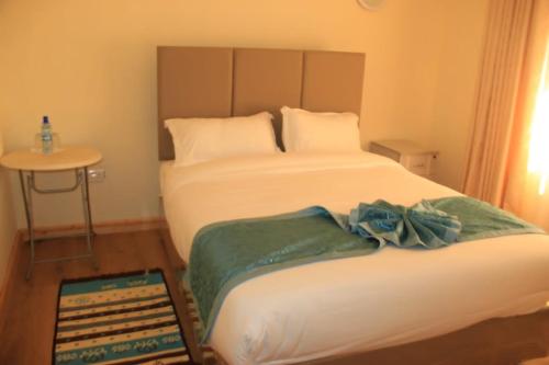 MweigaJuniper Green Gardens Resort.的一间卧室配有两张床和一张小桌子及一张桌子