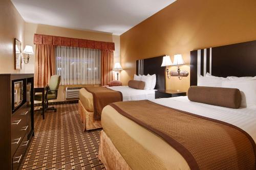 休斯顿Days Inn & Suites by Wyndham Sam Houston Tollway的酒店客房设有两张床和电视。