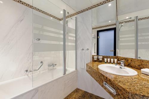莱比锡莱比锡威斯汀酒店的浴室配有水槽、淋浴和浴缸。