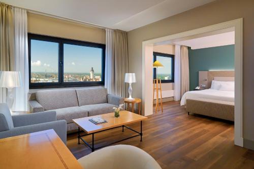 莱比锡莱比锡威斯汀酒店的酒店客房设有一张沙发和一张床,还有一间享有美景的客房。