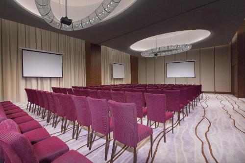 秦皇岛秦皇岛北戴河喜来登酒店的一间会议室,配有紫色椅子和白色屏幕
