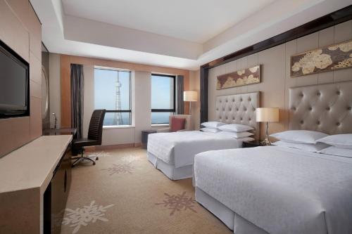 大庆大庆富力喜来登酒店的酒店客房设有两张床、一张桌子和一台电视。