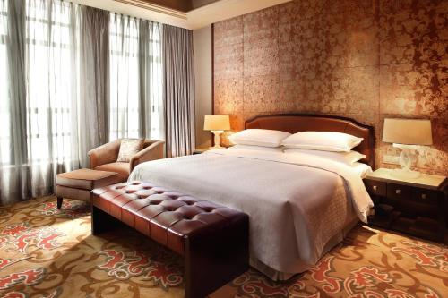江阴江阴黄嘉喜来登酒店的酒店客房带一张大床和一把椅子