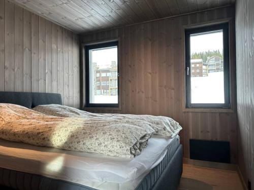 哈山Hafjell - Penthouse - ski in/out的一间卧室设有一张床和两个窗户。