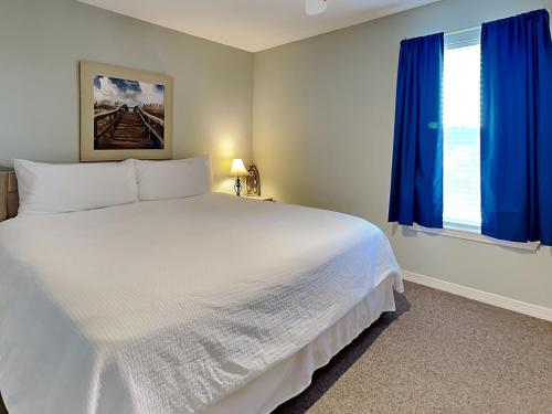 佩尔迪多基Grand Caribbean #306 West的卧室配有一张带蓝色窗帘的大型白色床