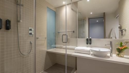 都柏林吉普森酒店的一间带玻璃淋浴和水槽的浴室