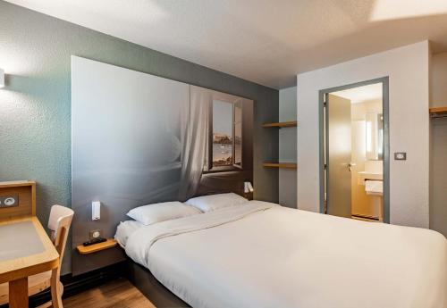 圣马丁德斯查B&B HOTEL Morlaix的卧室配有一张白色的大床和一张桌子