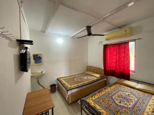 达博利Aviraj Nivas的客房设有两张床和一个带红色窗帘的窗户。