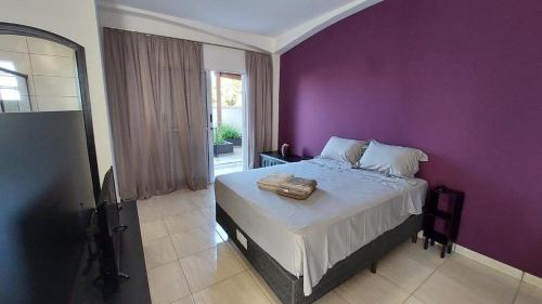 索罗卡巴Estúdios Jardim Emília的一间卧室设有紫色墙壁和一张床