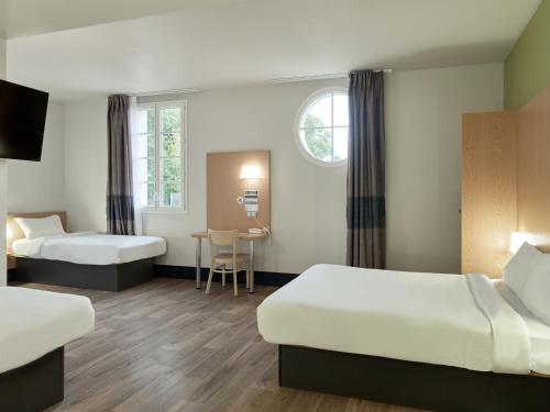 马尼库尔勒翁格尔B&B HOTEL près de Disneyland Paris的酒店客房设有两张床和一张桌子。