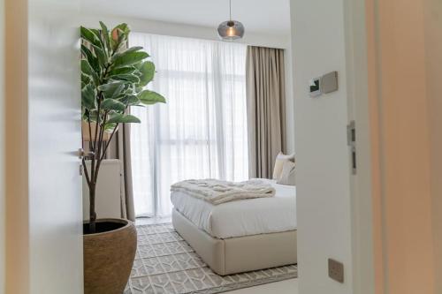 迪拜Clever Guest Beach Vista 1的一间卧室配有一张床和盆栽植物