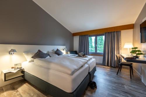 莱普海姆Hotel Leipheim Süd的酒店客房设有一张大床和一张书桌。