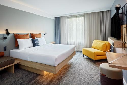 波鸿Moxy Bochum的酒店客房设有一张大床和一张黄色椅子