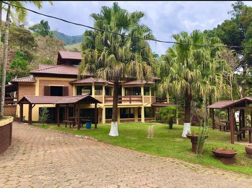 德尔芬莫雷拉hotel fazenda das montanhas的一座棕榈树大房子前面