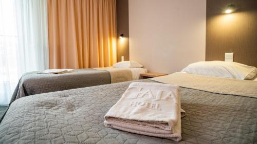 华沙佳雅酒店的酒店客房,配有两张床,床上有酒店住宿标志