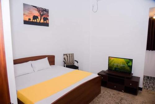 IbbagomuwaLotus cool hotel and restaurant的一间卧室配有一张床和一台平面电视
