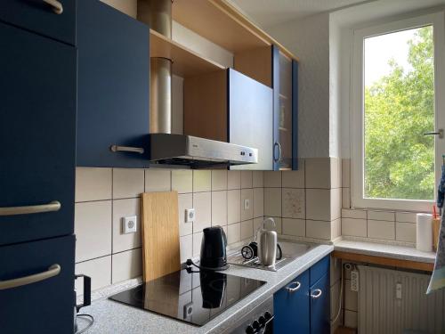 伊瑟隆Wohnen am Wanderbahnhof Iserlohn的厨房配有蓝色橱柜、炉灶和窗户。