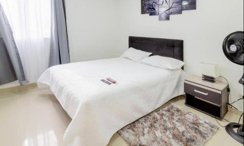 卡利Beautiful Apartment en Cali Colombia的一间卧室配有一张带白色床单和地毯的床。