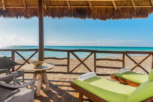 普拉亚卡门Mahekal Beach Front Resort & Spa的一个带桌椅的度假庭院和大海
