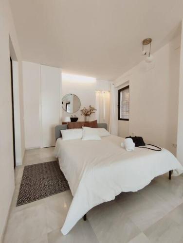 塞维利亚Antigua Casa Hermandad的白色卧室设有一张大床和镜子