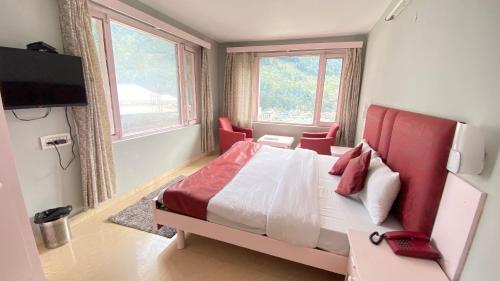 马拉里Hotel Mountain Meadows的一间卧室配有一张红色床头板的床和两个窗户