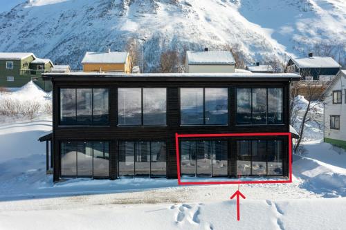 ToftaSkipperhuset leilighet nr 3的雪中的房子,上面有红箭