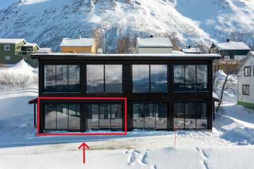 ToftaSkipperhuset leilighet nr 4的雪中的房子,上面有红箭