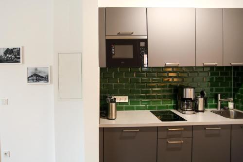 梅尔布施Green46的厨房设有水槽和绿色瓷砖墙