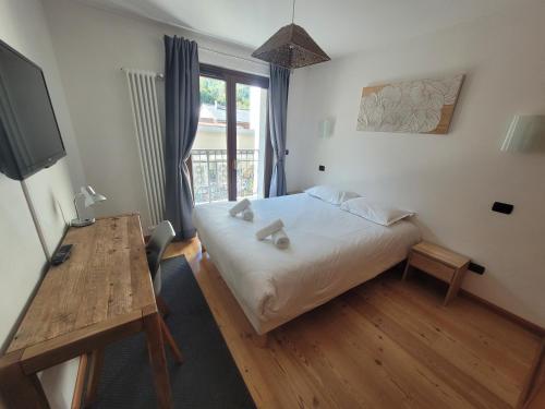 夏蒙尼-勃朗峰4-star apartments in Chamonix centre with free private parking的一间卧室配有一张床、一张桌子和一个窗户。