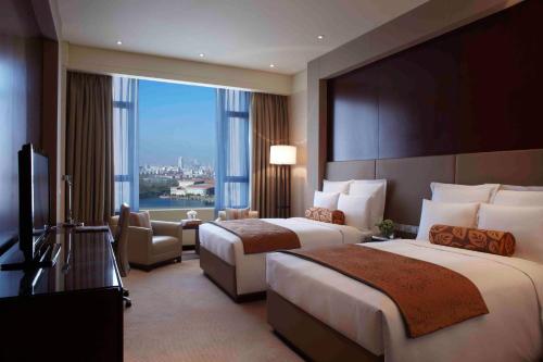 天津万丽天津宾馆的酒店客房设有两张床和大窗户。
