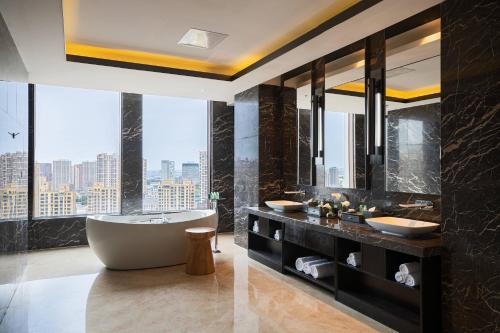 沈阳沈阳太阳狮万丽酒店  的带浴缸和两个盥洗盆的浴室以及大窗户。
