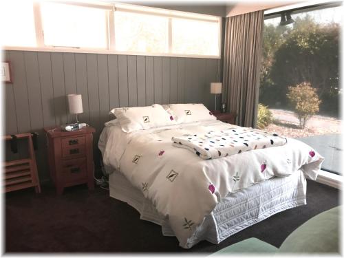 Pukerua BayPeaceful Pukerua Bay的卧室配有一张带白色棉被的床和窗户。