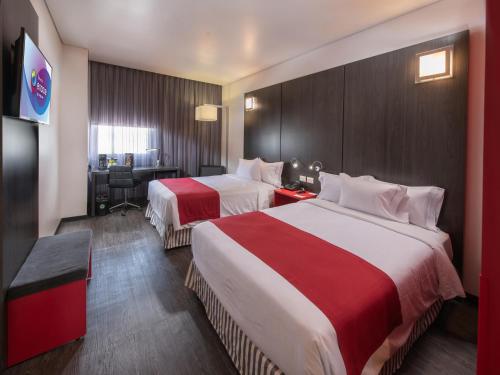 阿瓜斯卡连特斯Ramada Encore by Wyndham Aguascalientes的酒店客房配有两张床和一张书桌