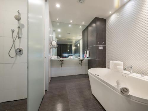 阿瓜斯卡连特斯Ramada Encore by Wyndham Aguascalientes的白色的浴室设有浴缸和水槽。
