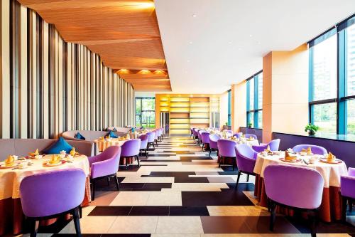 广州Aloft Guangzhou University Park的一间带桌子和紫色椅子的用餐室
