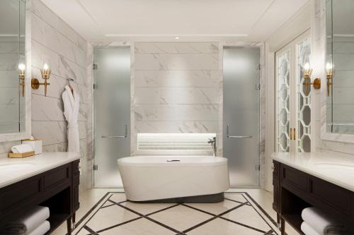 银川银川喜来登酒店的浴室配有卫生间、两个盥洗盆和浴缸。
