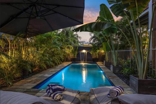 Stuart ParkLush Tropical Paradise Home - Darwin City的后院的游泳池,种植了植物,配有遮阳伞