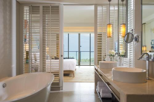 三亚三亚海棠湾万丽度假酒店的一间带两个盥洗盆和浴缸的浴室以及一间卧室