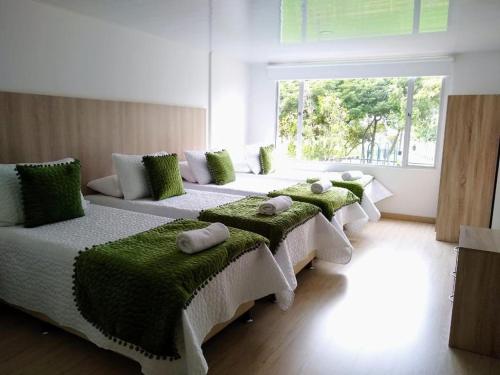 波哥大FEDERMAN PARK HOTEl的一间设有四张床的客房,配有绿色靠垫