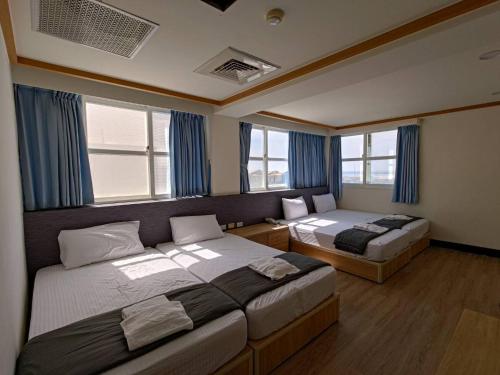 Huxi龙门海景渡假会馆  的卧室设有两张床,配有蓝色窗帘和窗户